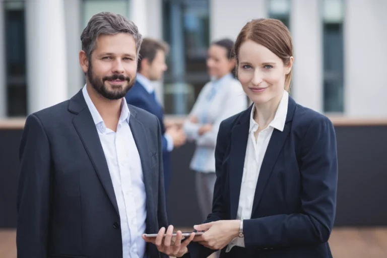 Ein Manager und eine Managerin stehen mit einem Pad und diskutieren die Hindernisse, eine berufliche Ver?nderung anzugehen.